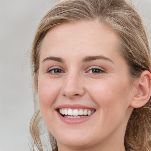 Joyful white young-adult female with long  brown hair and blue eyes