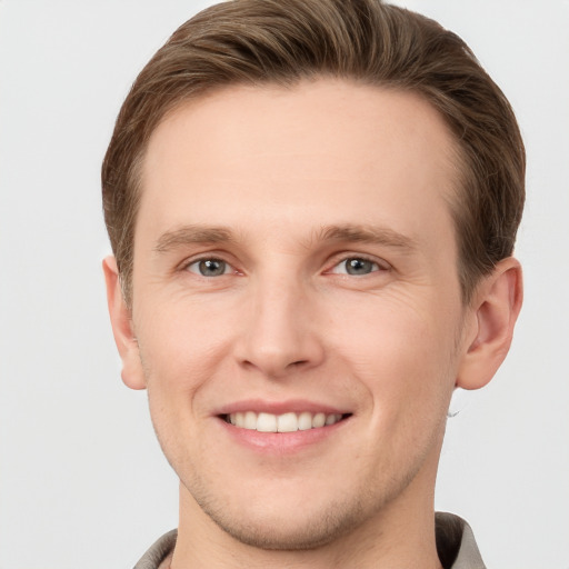 Joyful white young-adult male with short  brown hair and grey eyes