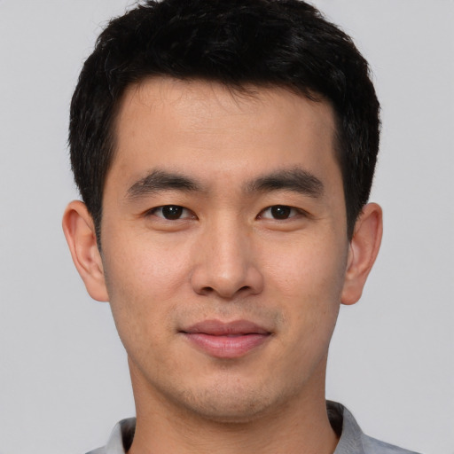Joyful asian young-adult male with short  brown hair and brown eyes