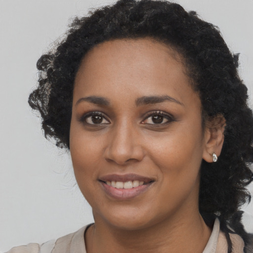 Joyful black young-adult female with long  black hair and brown eyes