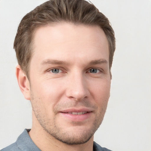 Joyful white young-adult male with short  brown hair and grey eyes