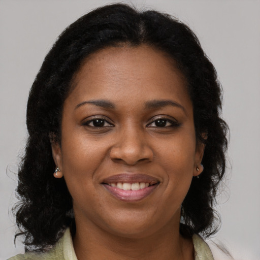 Joyful black young-adult female with long  brown hair and brown eyes