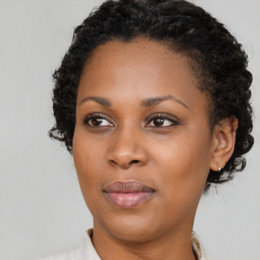 Joyful black young-adult female with short  black hair and brown eyes