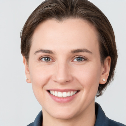 Joyful white young-adult female with medium  brown hair and grey eyes