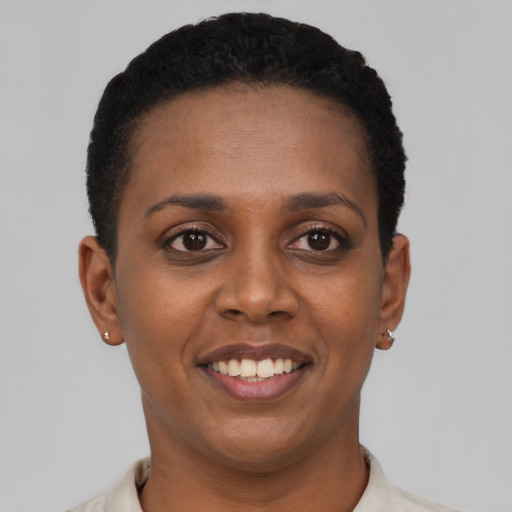 Joyful black young-adult female with short  black hair and brown eyes