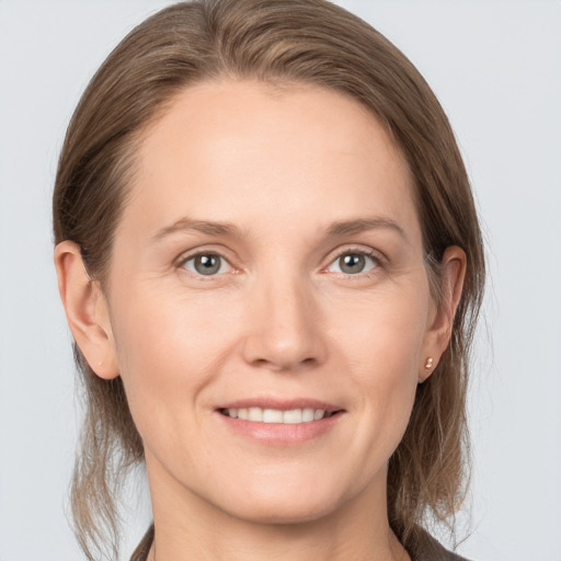 Joyful white young-adult female with medium  brown hair and grey eyes