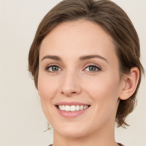 Joyful white young-adult female with medium  brown hair and green eyes