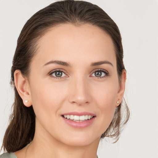 Joyful white young-adult female with medium  brown hair and grey eyes