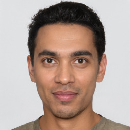 Joyful latino young-adult male with short  black hair and brown eyes
