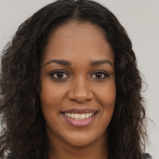 Joyful black young-adult female with long  brown hair and brown eyes
