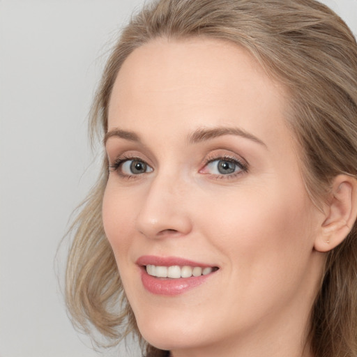 Joyful white young-adult female with long  brown hair and blue eyes