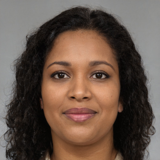 Joyful black young-adult female with long  brown hair and brown eyes