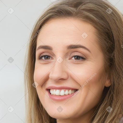 Joyful white young-adult female with long  brown hair and brown eyes