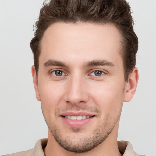 Joyful white young-adult male with short  brown hair and grey eyes