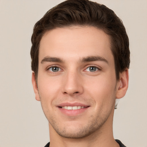 Joyful white young-adult male with short  brown hair and grey eyes