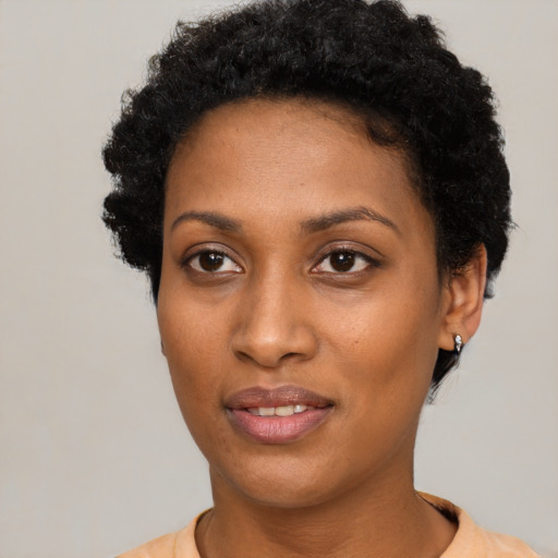 Joyful black young-adult female with short  black hair and brown eyes