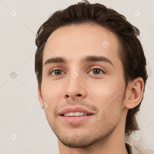 Joyful white young-adult male with short  brown hair and grey eyes