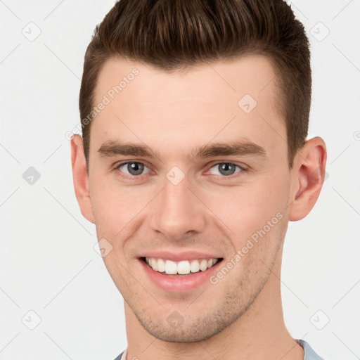 Joyful white young-adult male with short  brown hair and grey eyes