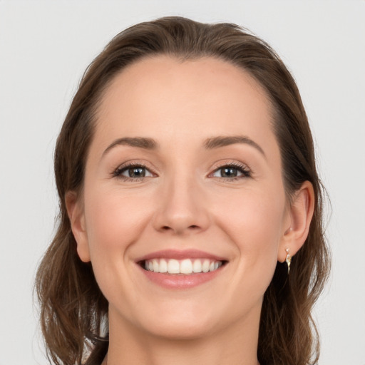 Joyful white young-adult female with long  brown hair and grey eyes