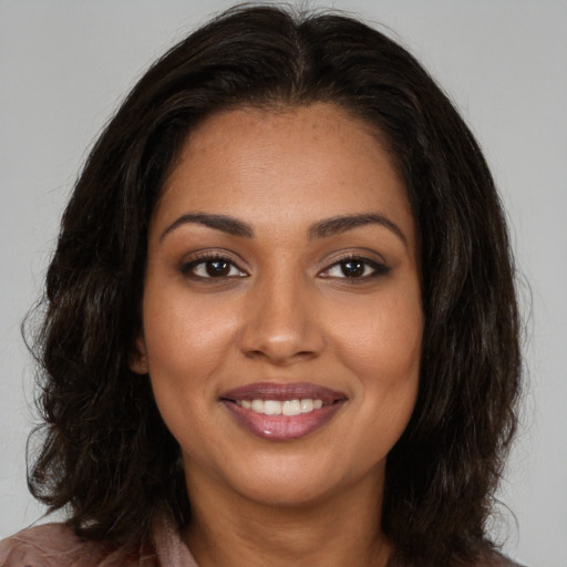 Joyful black young-adult female with long  brown hair and brown eyes