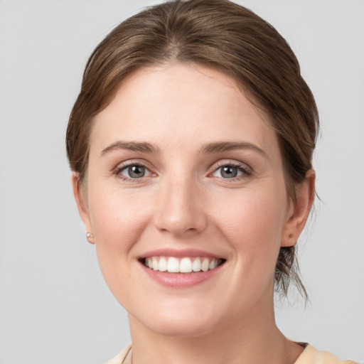 Joyful white young-adult female with medium  brown hair and grey eyes