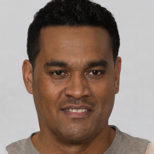 Joyful black young-adult male with short  black hair and brown eyes