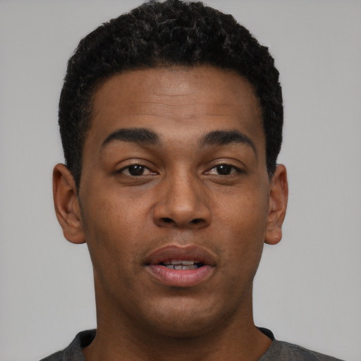 Joyful black young-adult male with short  black hair and brown eyes