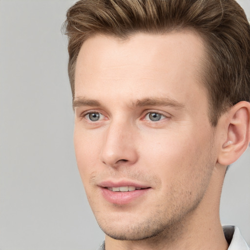 Joyful white young-adult male with short  brown hair and grey eyes