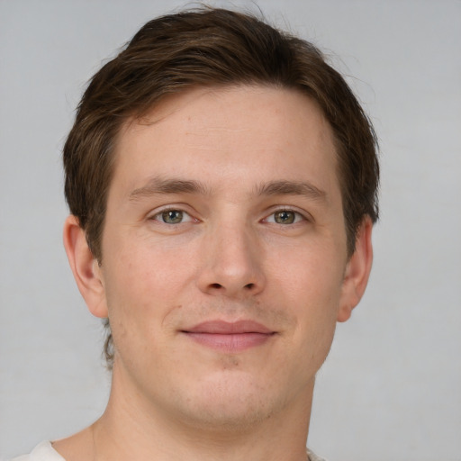 Joyful white young-adult male with short  brown hair and grey eyes