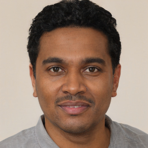 Joyful black young-adult male with short  black hair and brown eyes
