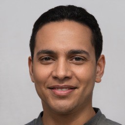 Joyful latino young-adult male with short  black hair and brown eyes