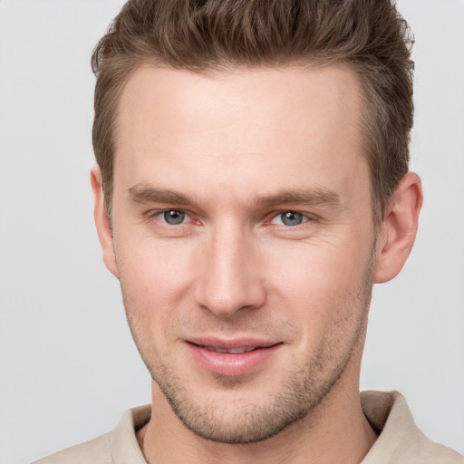 Joyful white young-adult male with short  brown hair and grey eyes