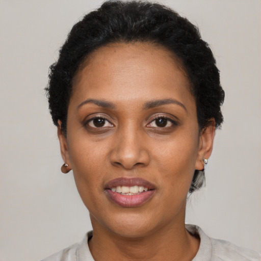 Joyful black young-adult female with short  black hair and brown eyes