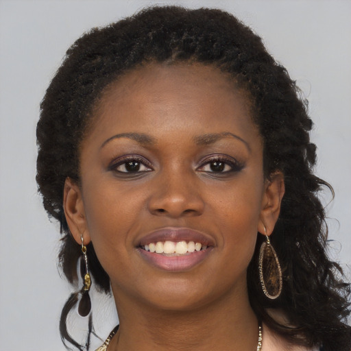 Joyful black young-adult female with long  brown hair and brown eyes