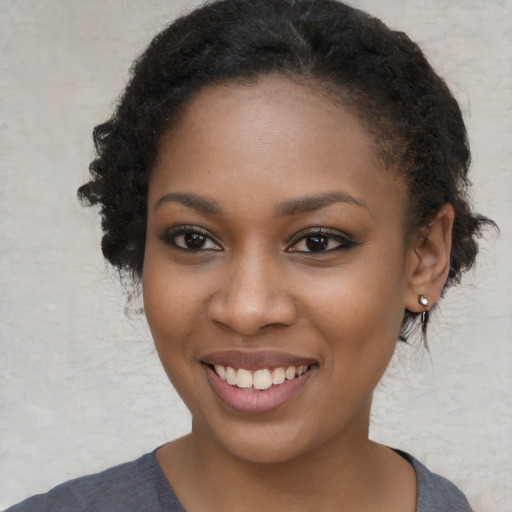 Joyful black young-adult female with long  brown hair and brown eyes