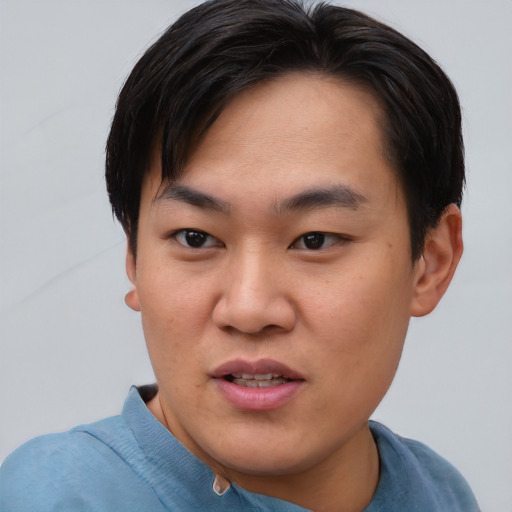 Joyful asian young-adult male with short  brown hair and brown eyes