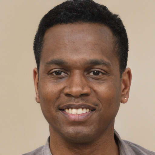 Joyful black young-adult male with short  black hair and brown eyes