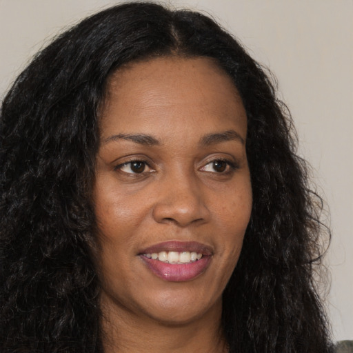 Joyful black young-adult female with long  brown hair and brown eyes