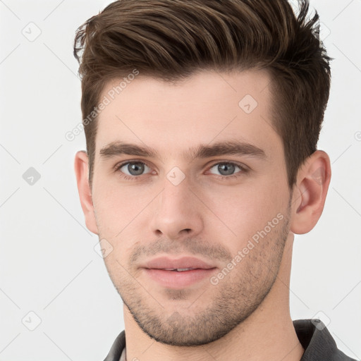 Joyful white young-adult male with short  brown hair and grey eyes