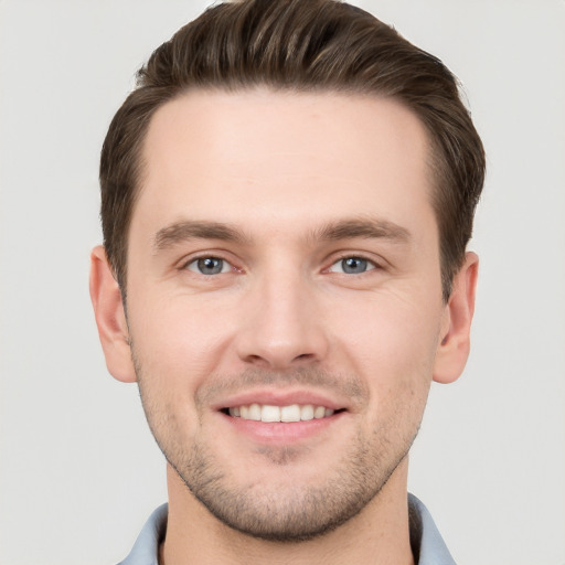 Joyful white young-adult male with short  brown hair and grey eyes