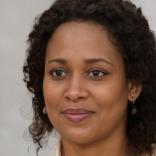 Joyful black young-adult female with long  brown hair and brown eyes