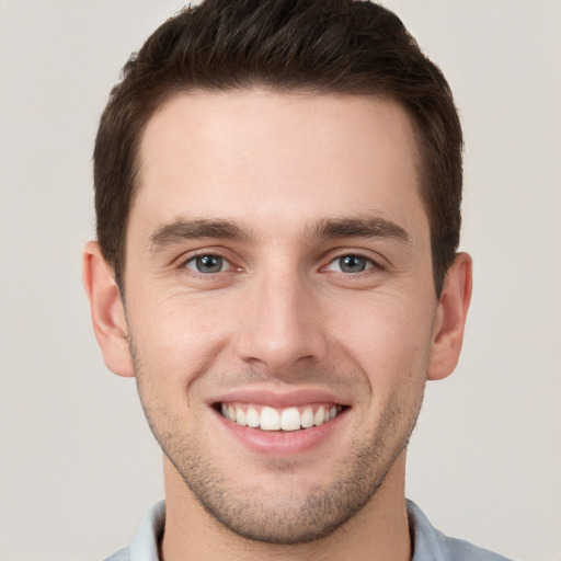 Joyful white young-adult male with short  brown hair and grey eyes