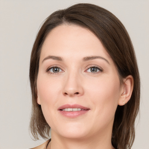 Joyful white young-adult female with medium  brown hair and grey eyes