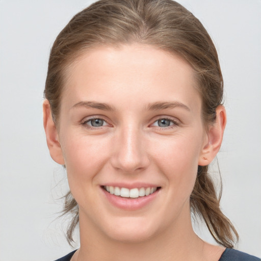 Joyful white young-adult female with medium  brown hair and grey eyes