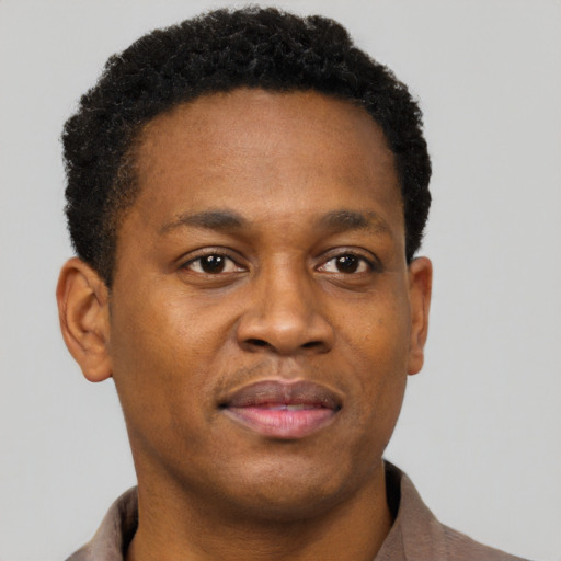 Joyful black young-adult male with short  brown hair and brown eyes