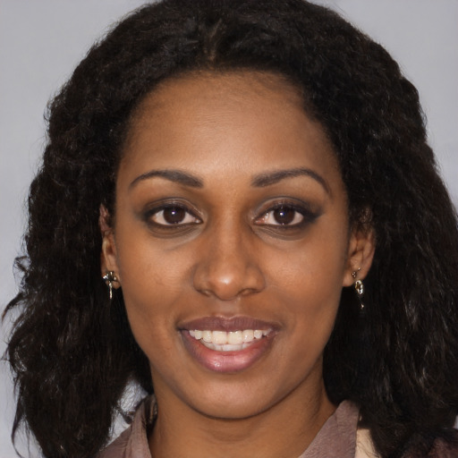 Joyful black young-adult female with long  brown hair and brown eyes