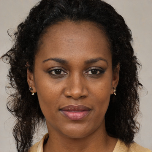 Joyful black adult female with long  brown hair and brown eyes