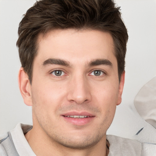 Joyful white young-adult male with short  brown hair and grey eyes