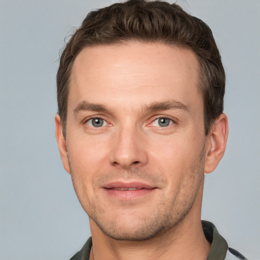 Joyful white young-adult male with short  brown hair and grey eyes