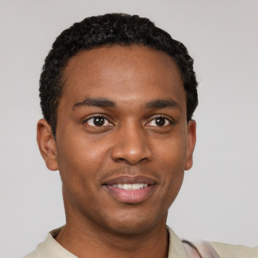 Joyful black young-adult male with short  black hair and brown eyes